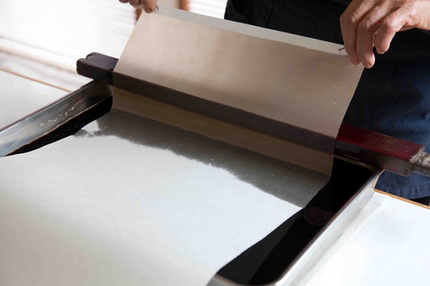 バットに染料を張り、紙を漬けて染めているところです